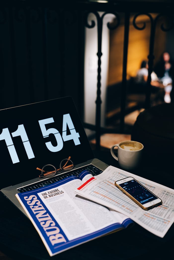 Modern workspace with business newspaper, smartphone, and laptop displaying the time, creating a productive ambiance.